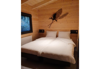 Slaapkamer van een 4-persoons wellness lodge in Nederland met houten muren en twee aparte bedden.