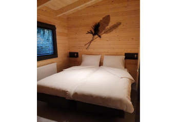 Bedroom in a 4-person wellness lodge in the Netherlands with wooden walls, twin beds and cozy decor.