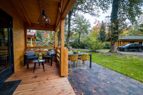 Outdoor terrace and dining area at a 4-person wellness lodge surrounded by greenery in the Netherlands.