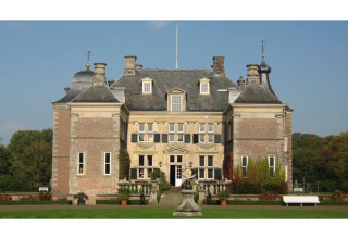 Foto de un gran albergue de estilo histórico, con jardín, césped y fachada simétrica bajo la luz del día.