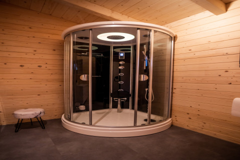 Modern round shower cabin in a wooden wellness lodge in the Netherlands, featuring warm ambient lighting.