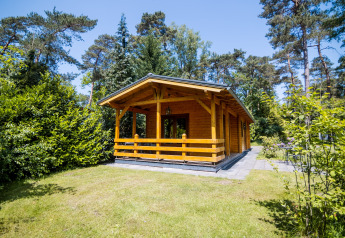 Lodge bien-être pour 2 personnes en bois, entouré d’arbres, avec terrasse et pelouse, ambiance naturelle.