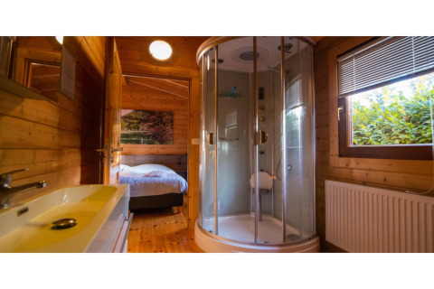 Salle de bain d’un lodge bien-être pour 2 personnes aux Pays-Bas, avec douche, lavabo et vue chambre.