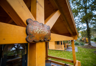 Houten bord met 'Norse' aan een wellness lodge voor 4 personen in Nederland, omgeven door groen.