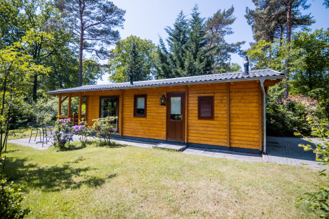 En lille træhytte omgivet af natur, beliggende i Holland, kendt som '2-personers wellness lodge'.