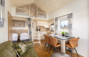 Gemütliches Tiny House im Ferienpark Tolplas 19, Niederlande, mit Küche und Hochbett in hellem Design.