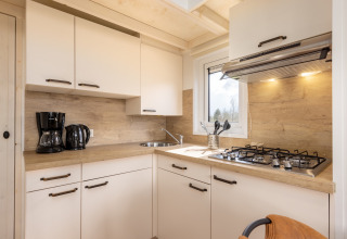 Cocina moderna de casa pequeña con estufa de gas, fregadero, cafetera y armarios blancos en Tolplas 19.
