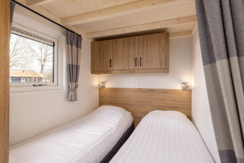 Helles Schlafzimmer mit zwei Einzelbetten, Holzschrank und Fenster im Tiny House Holiday Park Tolplas 19.