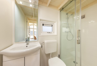 Lille, moderne badeværelse på Holiday park «Tolplas 19» i Holland, med brusekabine, toilet og håndvask.
