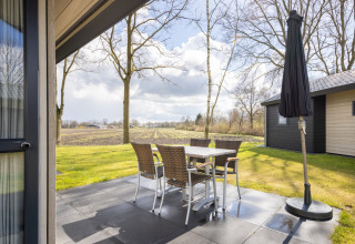 Udendørs terrasse på Holiday park Tolplas 19 med bord og stole, udsigt over landskab i Holland.