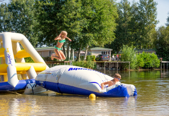 Zwei Kinder spielen auf einer aufblasbaren Wasserplattform im Holiday Park Tolplas 19 in den Niederlanden.