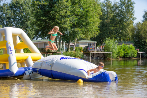Zwei Kinder spielen auf einer aufblasbaren Wasserplattform im Holiday Park Tolplas 19 in den Niederlanden.