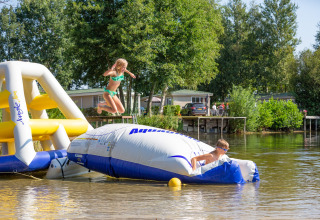 Two children play on an inflatable water playground at tiny house Holiday park Tolplas 19 in the Netherlands.