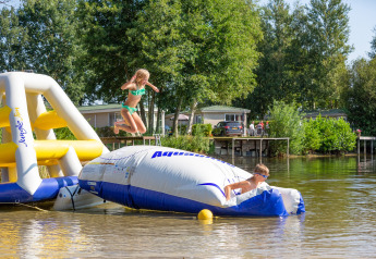 Zwei Kinder spielen auf einer aufblasbaren Wasserplattform im Holiday Park Tolplas 19 in den Niederlanden.