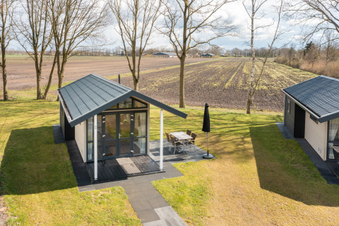 Klein huisje in vakantiepark Tolplas 19 in Nederland, met terras en uitzicht op het platteland.