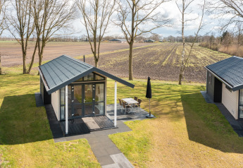Tiny house at Holiday Park Tolplas 19 in the Netherlands, with terrace, views of lawn and farmland.