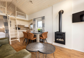 Helles Interieur eines Tiny Houses im Holiday Park Tolplas 19 mit Küche, Kamin, Loft und Essbereich.