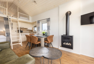 Helles Interieur eines Tiny Houses im Holiday Park Tolplas 19 mit Küche, Kamin, Loft und Essbereich.