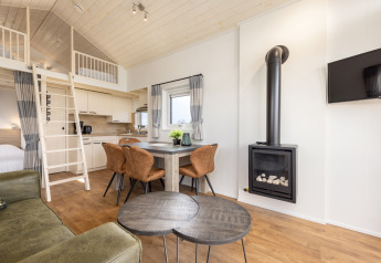Helles Interieur eines Tiny Houses im Holiday Park Tolplas 19 mit Küche, Kamin, Loft und Essbereich.