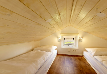 Zwei Einzelbetten in einem Dachzimmer mit Holzdecke und kleinem Fenster im Tiny House Tolplas 19.