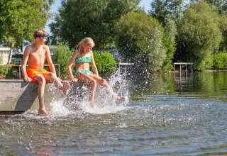 Dos niños chapotean con los pies en el agua en Holiday park Tolplas 19, Países Bajos.
