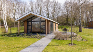 Moderne Ferienlodge im Holiday Park Tolplas 18 mit Glasfront, Terrasse und viel Natur rundum.