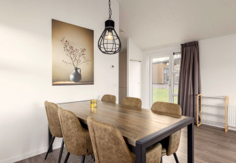 Essbereich in der Lodge im Holiday Park «Tolplas 18», Niederlande, mit Tisch, Stühlen und Wandbild.