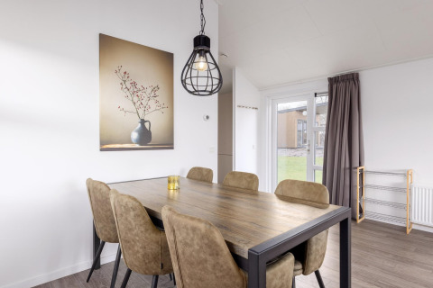 Essbereich in der Lodge im Holiday Park «Tolplas 18», Niederlande, mit Tisch, Stühlen und Wandbild.