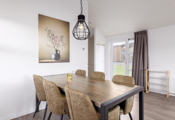 Essbereich in der Lodge im Holiday Park «Tolplas 18», Niederlande, mit Tisch, Stühlen und Wandbild.