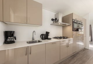 Modern kitchen at Holiday park Tolplas 18 in the Netherlands with beige cabinets, stove and appliances.