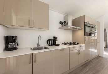 Moderne Küche im Holiday Park Tolplas 18 in den Niederlanden mit beigen Schränken und Geräten.
