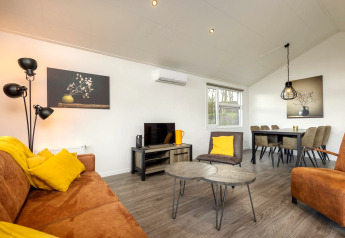 Lyst og moderne opholdsområde i feriepark Tolplas 18 i Holland, med gule puder og elegant indretning.
