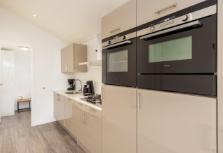 Cocina moderna con hornos empotrados, estufa de gas y cafetera en Holiday park Tolplas 18, Países Bajos.