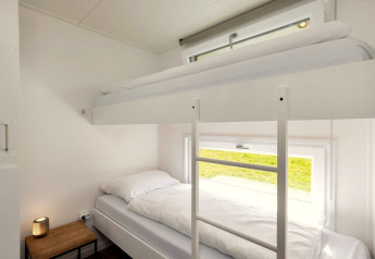 Modernes Etagenbett mit weißer Bettwäsche in einem hellen Zimmer im Holiday park „Tolplas 18“ in den Niederlanden.
