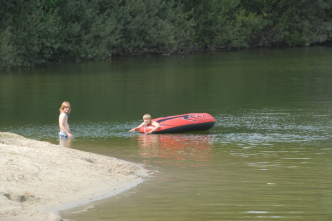 Twee kinderen spelen aan een meer met een opblaasboot bij Holiday park Tolplas 19 in Nederland.