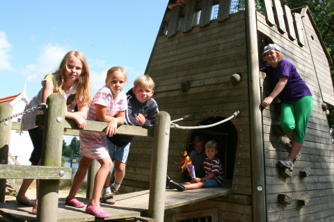 Børn og en voksen leger på en legeplads ved et feriehus i Holiday park Tolplas 19, Holland.