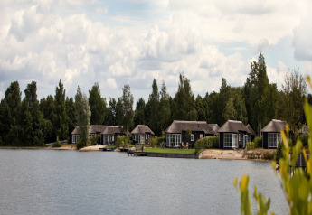Blick auf Ferienhäuser im Holiday Park Tolplas 19 in den Niederlanden am See mit Bäumen.