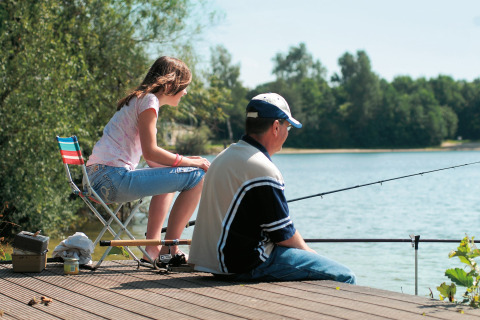 Un uomo e una ragazza pescano insieme su un pontile di legno al lago presso Holiday park «Tolplas 19» nei Paesi Bassi.
