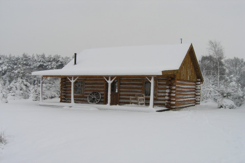 Eine Blockhütte namens American Log Cabin, bedeckt mit Schnee, in einer Winterlandschaft in den Niederlanden.