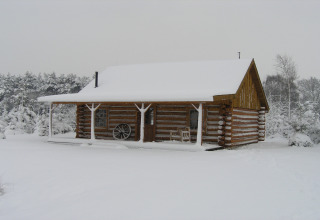 En tømmerhytte kaldet American Log Cabin dækket af sne i et vinterlandskab i Holland.