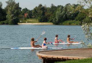 Quattro bambini seduti su paddleboard sul lago vicino a Holiday park Tolplas 19, circondati dalla natura olandese.