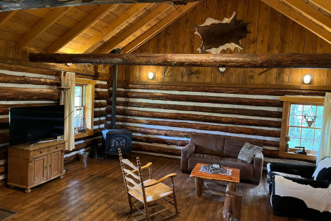 Rustikales Interieur einer amerikanischen Blockhütte in den Niederlanden mit Holzofen und Holzmöbeln.