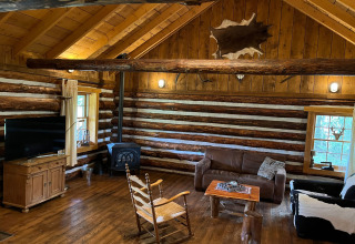 Rustikales Interieur einer amerikanischen Blockhütte in den Niederlanden mit Holzofen und Holzmöbeln.