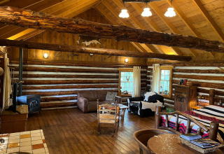Interno accogliente di una baita americana nei Paesi Bassi con travi di legno, divano e stufa a legna.