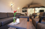 Wohnbereich in Residence De Eese 22 in den Niederlanden mit Sofas, Sesseln und einer Loft-Etage.
