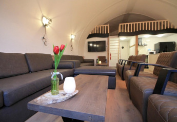 Wohnbereich in Residence De Eese 22 in den Niederlanden mit Sofas, Sesseln und einer Loft-Etage.