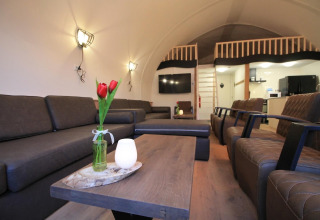 Moderne opholdsstue i Residence De Eese 22 i Holland med komfortable sofaer, lænestole og et loftrum.