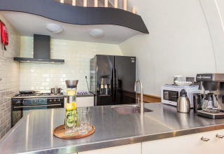Moderne keuken met zwart koelkast, roestvrijstalen werkblad en koffiezetapparaat in Residence De Eese 22.