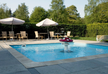 Außenpool mit Pilzbrunnen, Sonnenschirmen und Gartenmöbeln in einer Glamping-Unterkunft im Sommer.