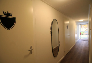 Hal bij Residence De Eese 22, Nederland, met ovale spiegel en deuren met schild en kroonsymbool.